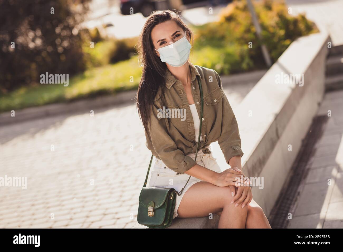 Photo portrait of cute girl wearing face mask sitting outside cafe Stock Photo