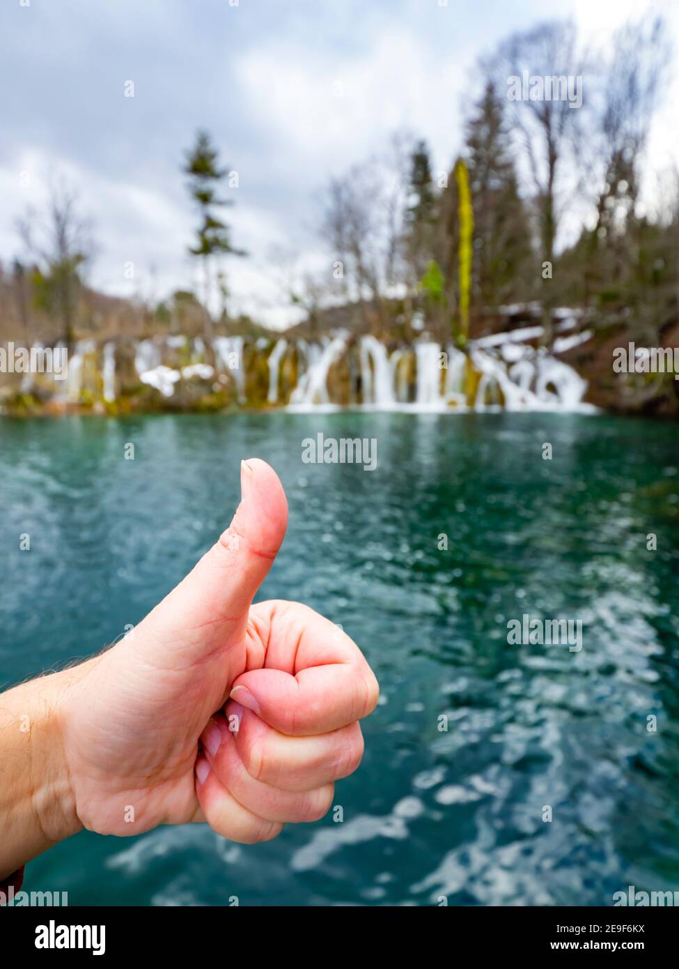 Hand its ok thumb up thumbup sign Lake with multiple small waterfalls in national park Plitvice lakes Croatia Europe Stock Photo