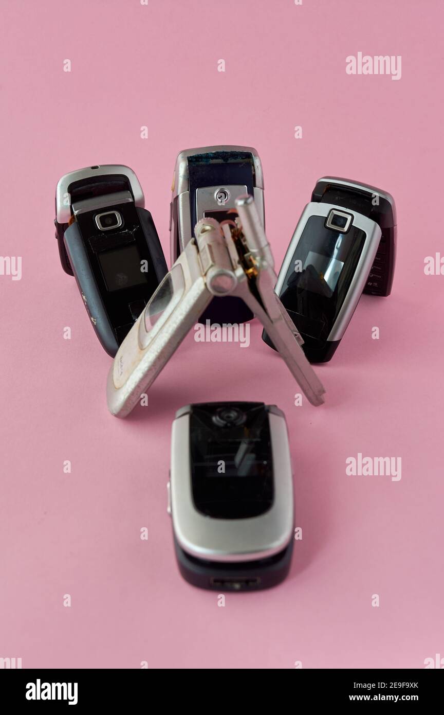 broken mobile phones, recycling technology, early 2000s on pink background and copy space,. Stock Photo