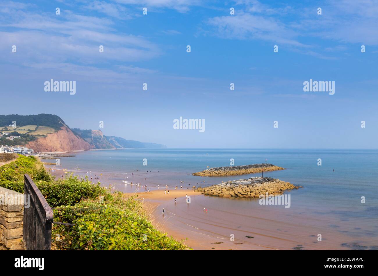 The sandy beach and rocky islands looking east at Sidmouth, a Devon coastal town on the Jurassic Coast World Heritage Site at low tide on a sunny day Stock Photo