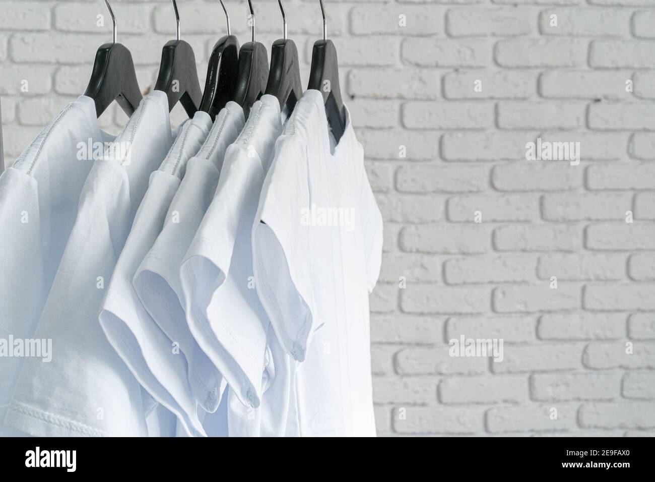 White t-shirt hanging on hanger against brick wall Stock Photo