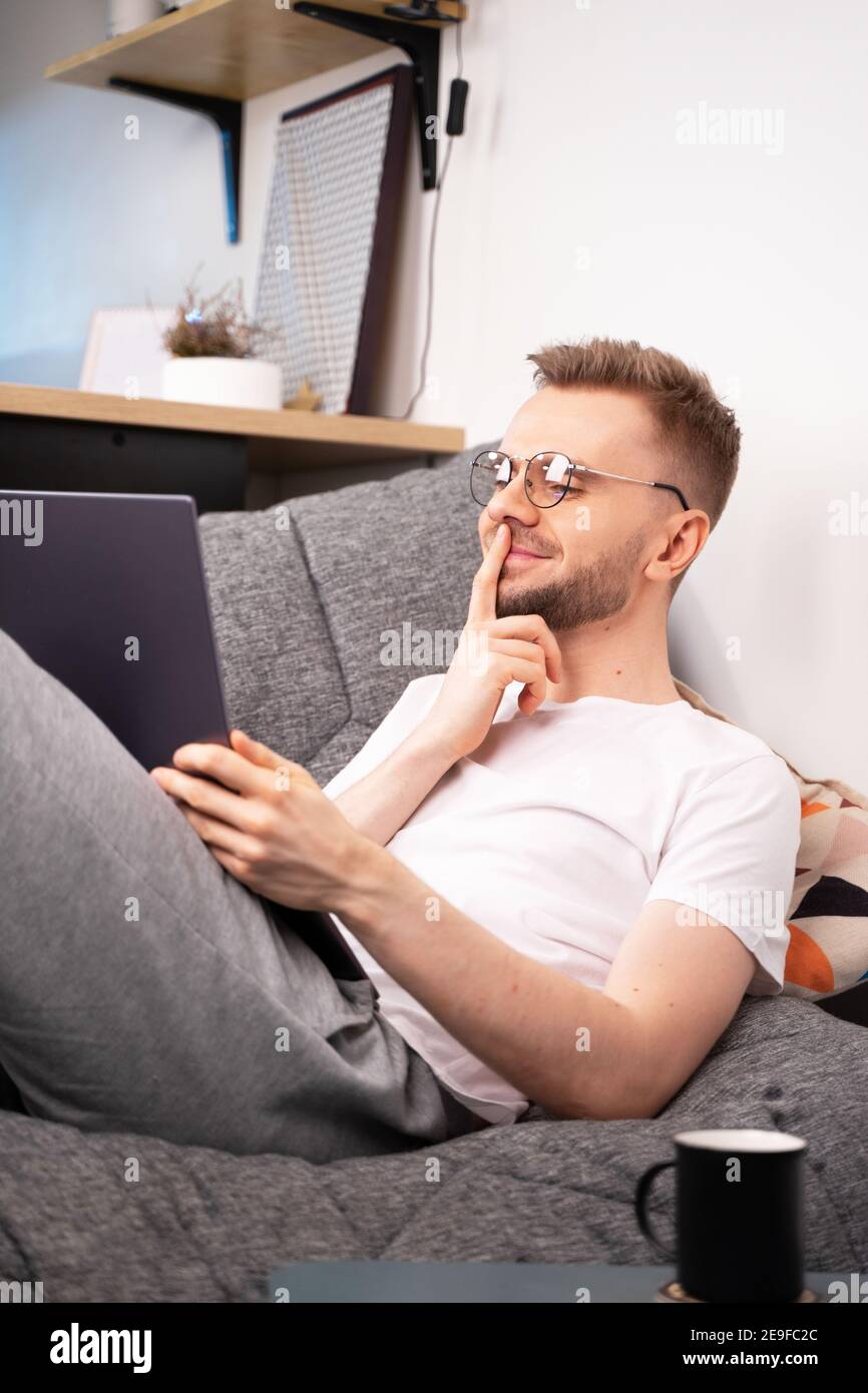 Young caucasian man programmer sit on sofa video calling remote friend woman talking in online webcam chat on laptop at home office. Distance dating Stock Photo