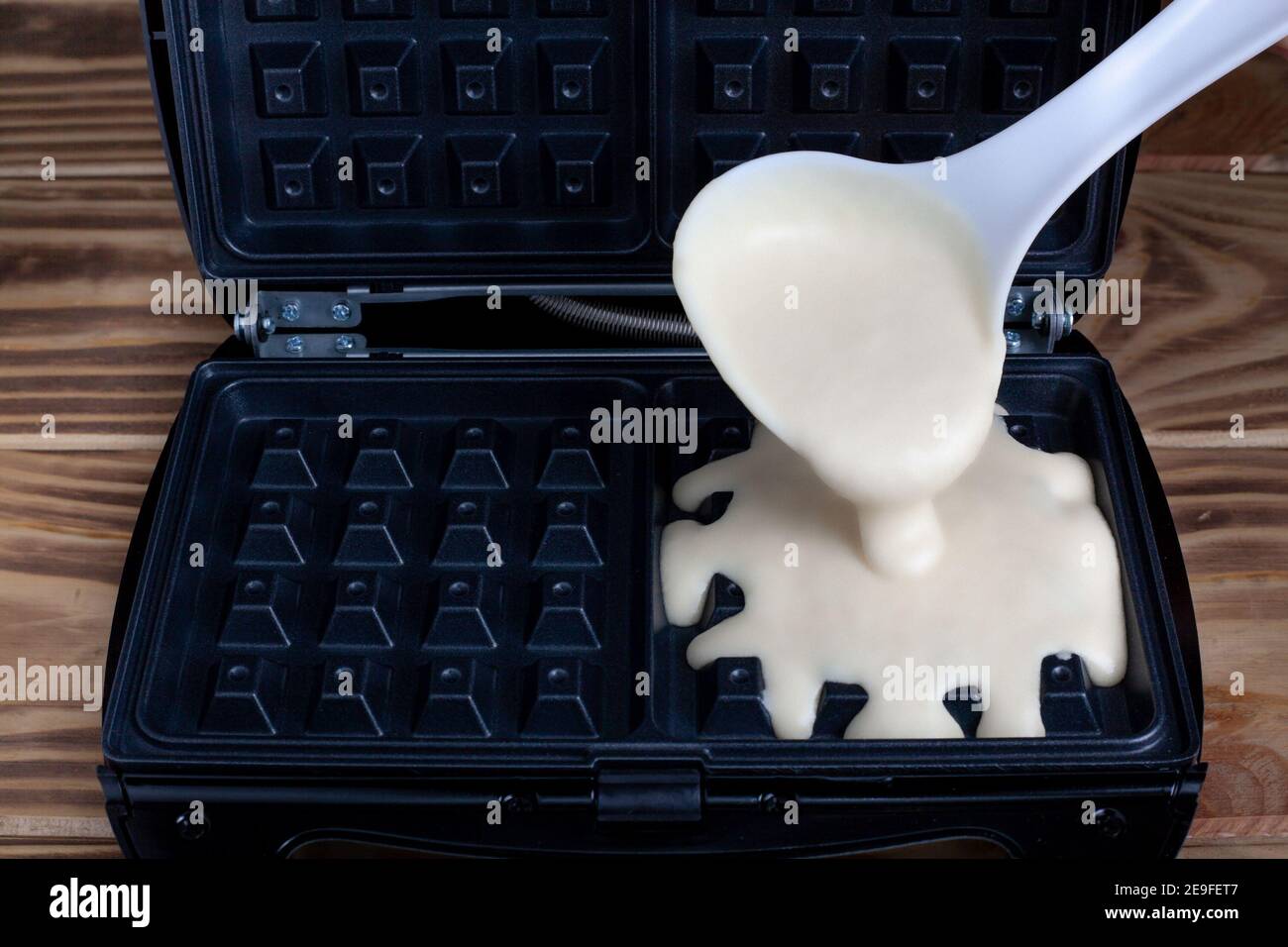 Waffle iron in the kitchen. Preparing homemade waffles, pouring a dough. Belgian viennese waffles Stock Photo