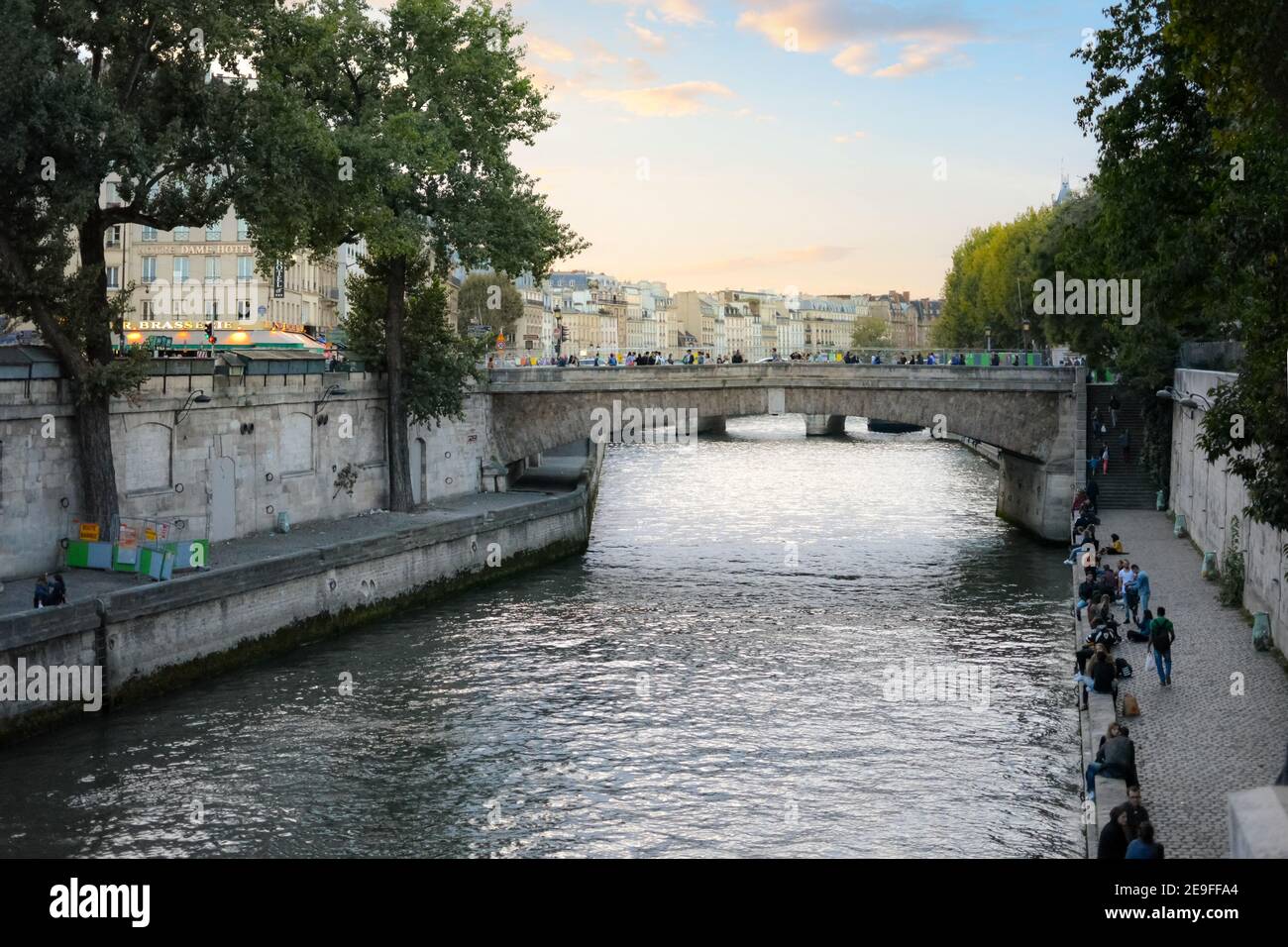 Local Parisians enjoy early evening strolling and relaxing on the banks of Seine river near the Ile de la Cite in Paris, France. Stock Photo