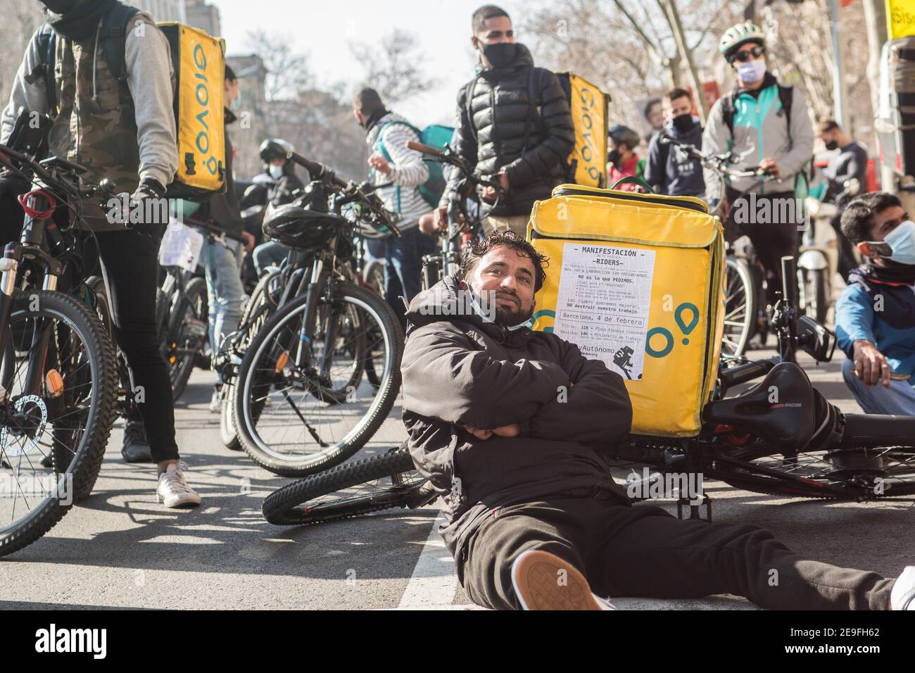 A protester sits on the floor with a bicycle and a Glovo bag during the  demonstration.Hundreds of delivery people from different home delivery  platforms such as Deliveroo, Uber Eats, Glovo, Stuart and