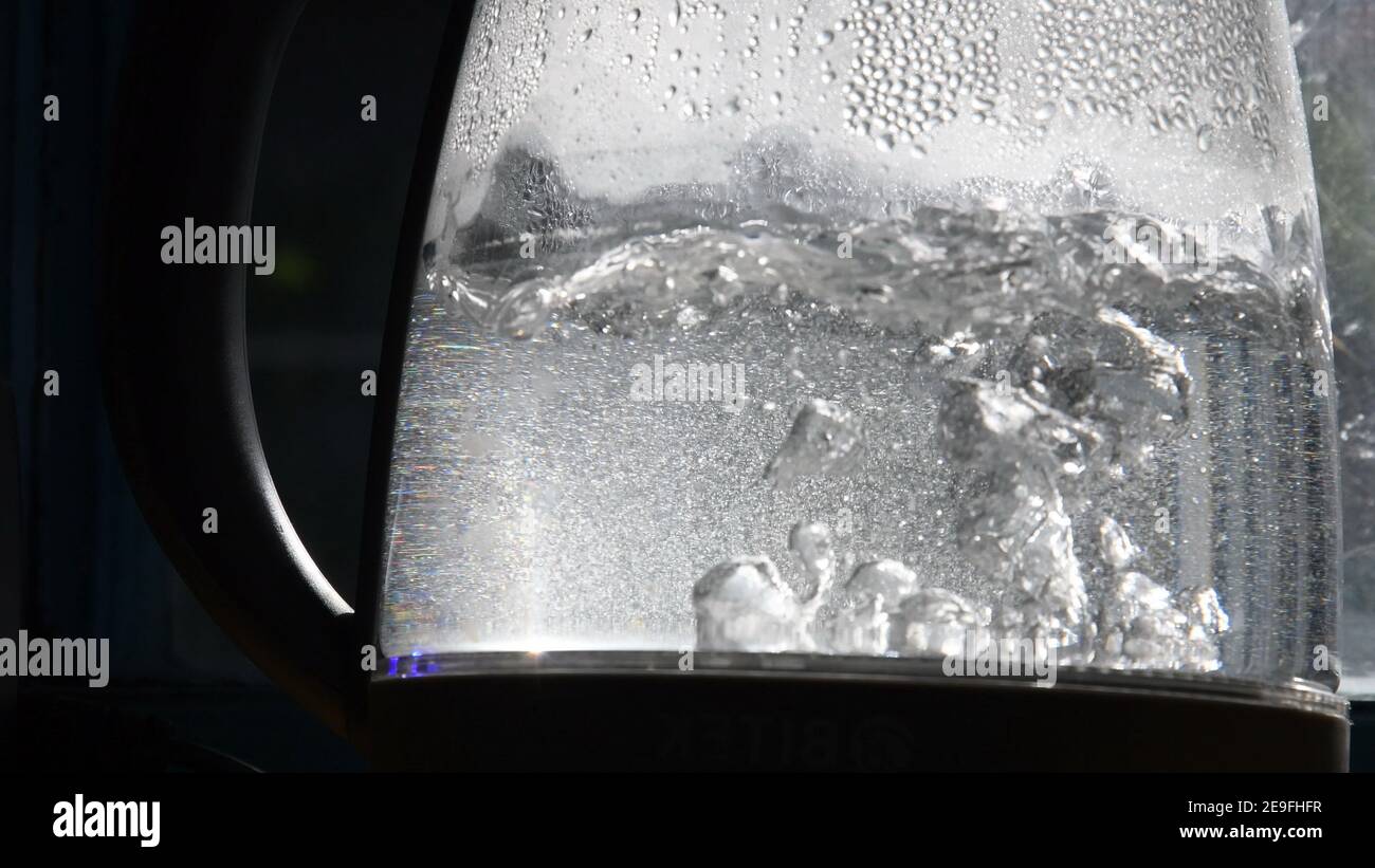 Defocused bubbles in hot water boiling inside glass teapot in bright