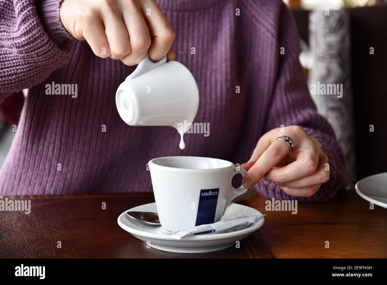 Young woman hands hold white ceramic milk jug with dripping drop into