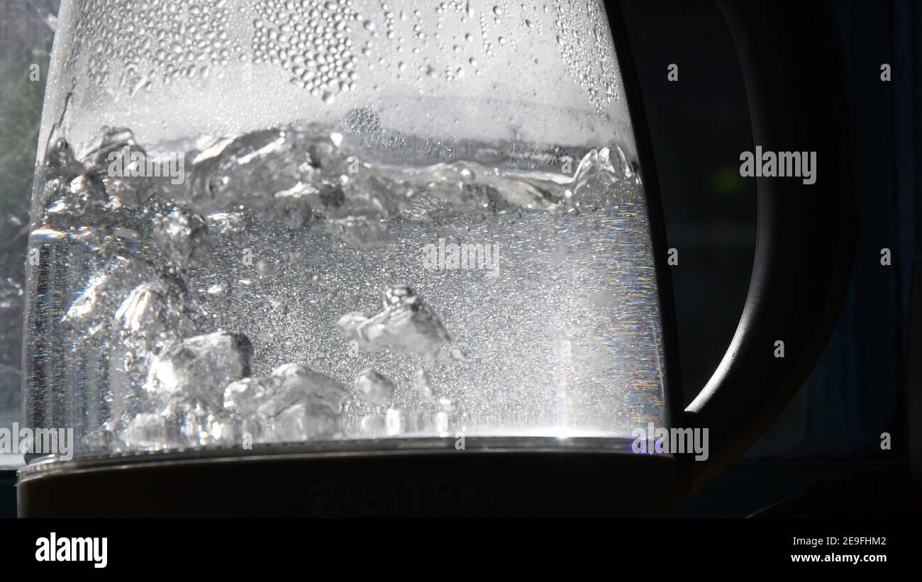 Defocused bubbles in hot water boiling inside glass teapot in bright