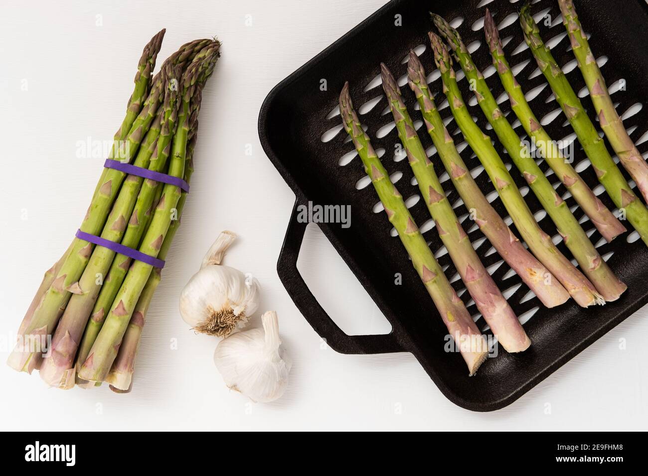 Asparagus and garlic being prepared for the grill on a white background Stock Photo