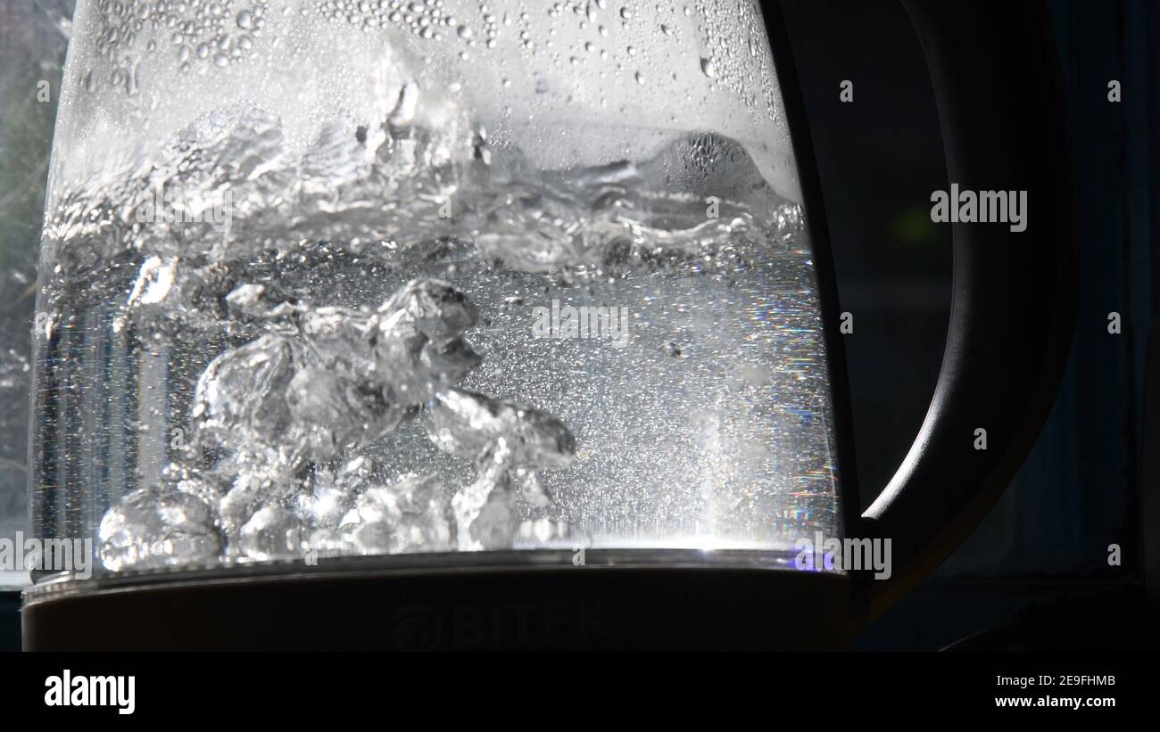 Defocused bubbles in hot water boiling inside glass teapot in bright