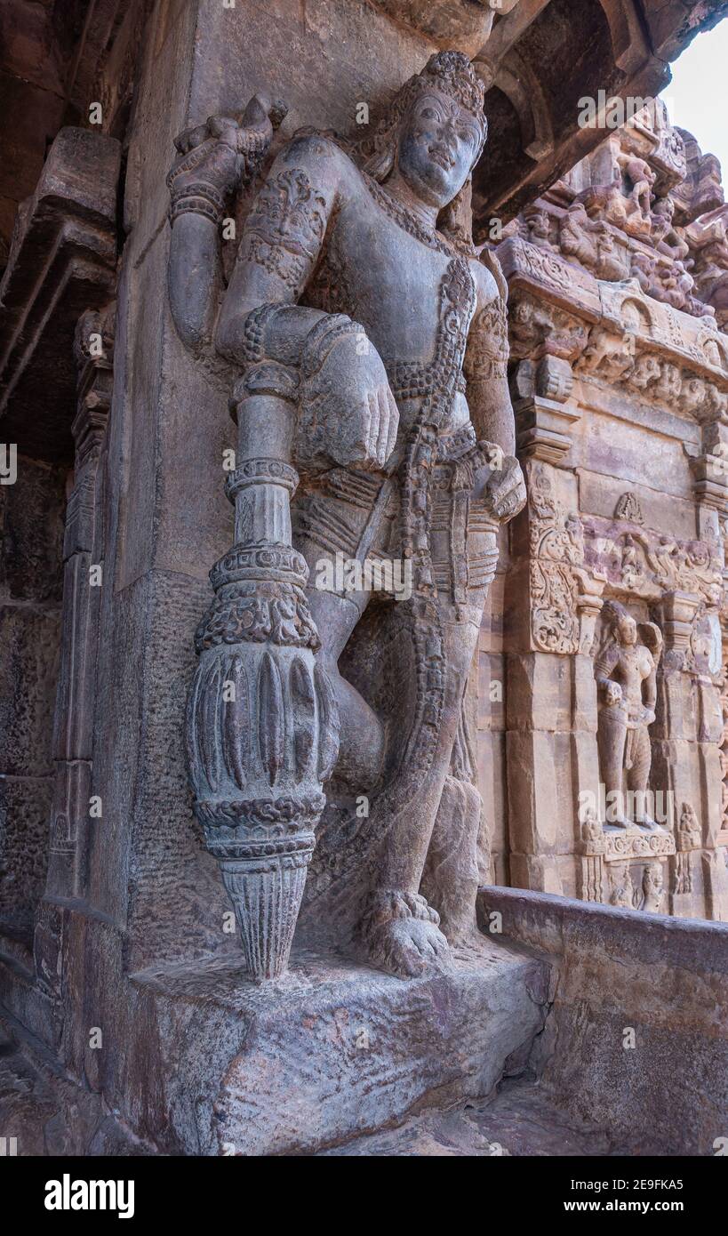 Bagalakote, Karnataka, India - November 7, 2013: Pattadakal temple complex. Giant gray stone statue of dwarapalaka guard at entrance to brown stone Vi Stock Photo