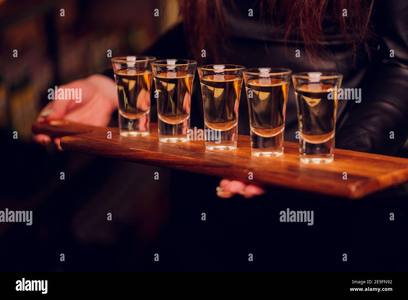 Variation of hard alcoholic shots served on bar counter. Blur bottles