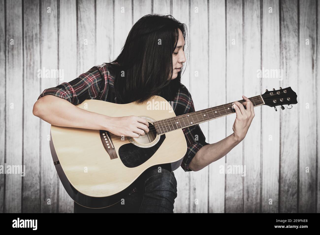 Portrait handsome young male guitarist with long hair sitting and