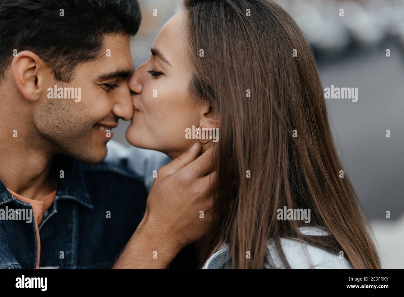 Young beautiful girl kissing his boyfriend's nose. Couple in love in the city. Urban lovestory Stock Photo