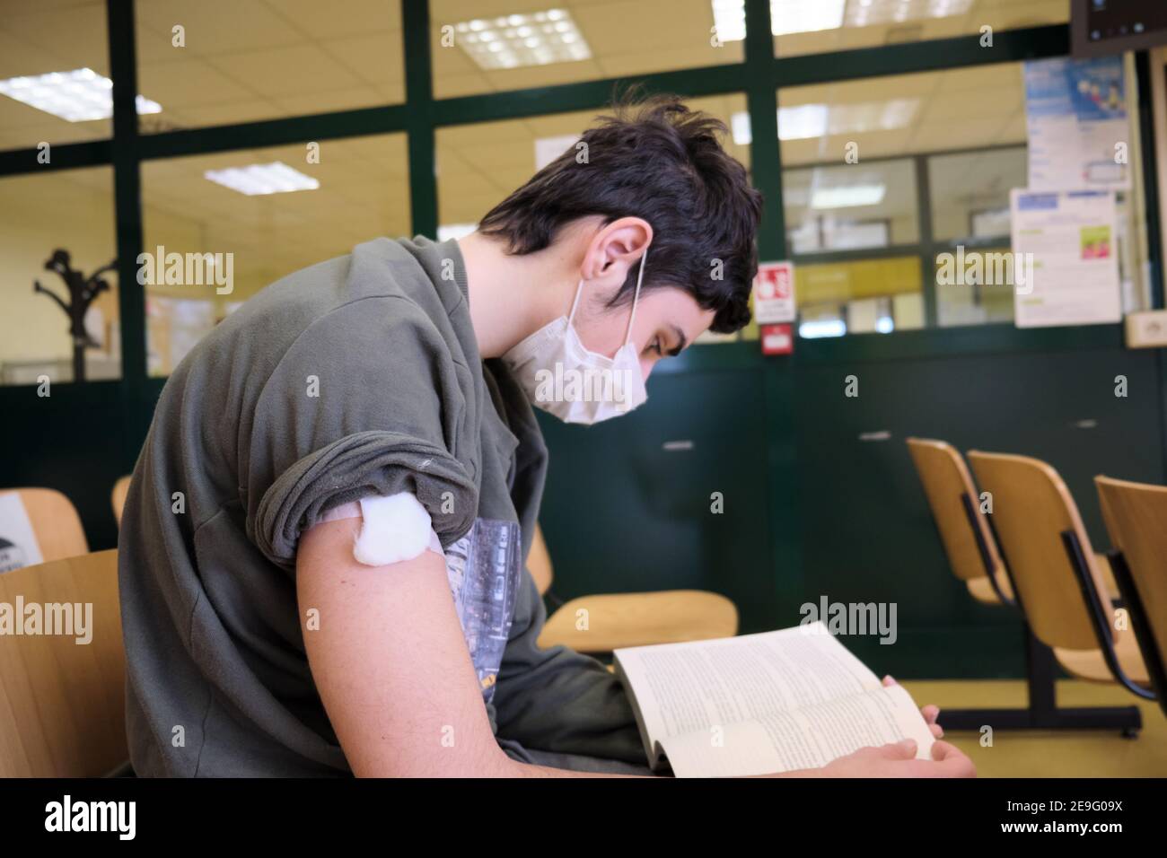 a guy reads a book in the hospital waiting room after making the vaccine Stock Photo