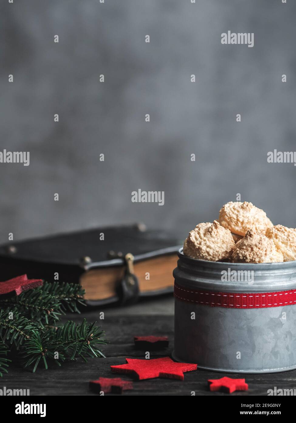 Christmas coconut meringue cookies in metal box and old bible on background. Dark and moody. Copy space. Stock Photo