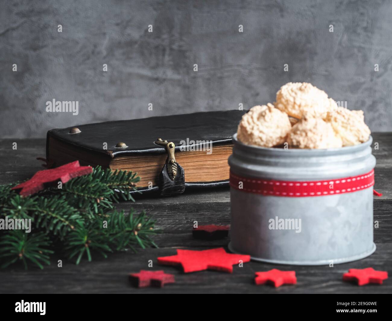 Christmas coconut meringue cookies in metal box and old bible on background. Dark and moody. Copy space. Horizontal shot. Stock Photo