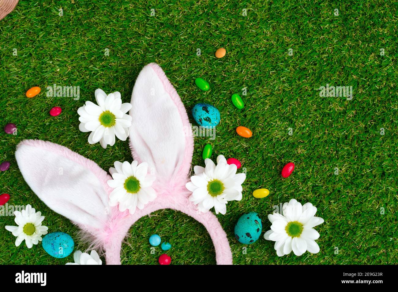 Colored eggs and vibrant candies on grass. Easter composition Stock Photo