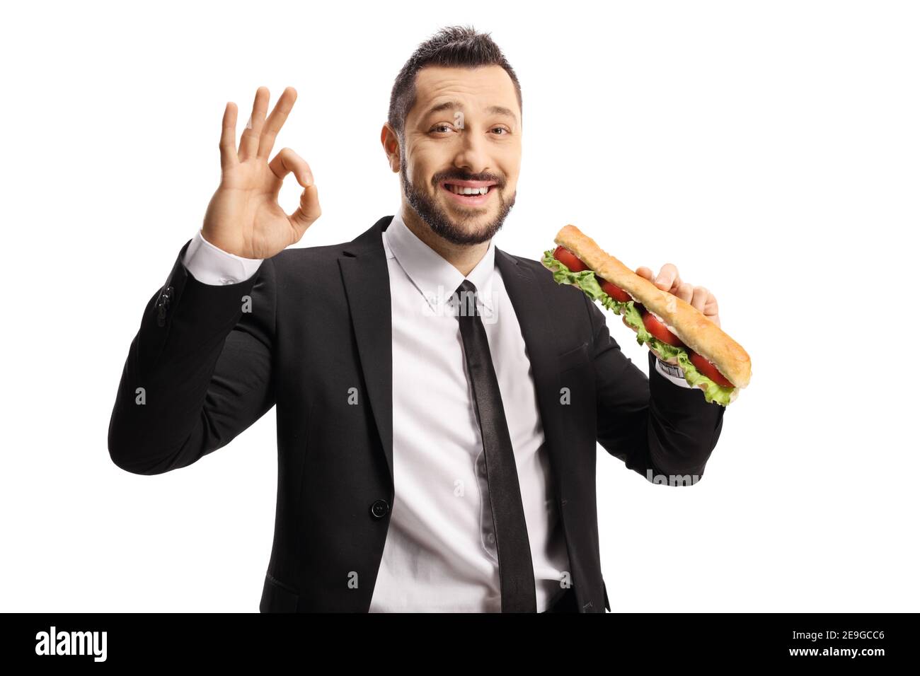 Businessman holding a sandwich in a baguette and gesturing ok sign isolated on white background Stock Photo