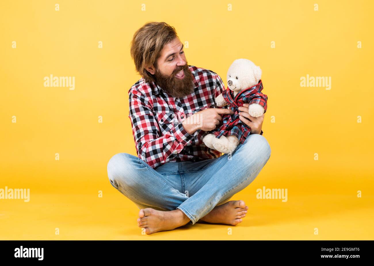 brutal bearded man wear checkered shirt having lush beard and moustache with teddy bear toy, valentines day. Stock Photo