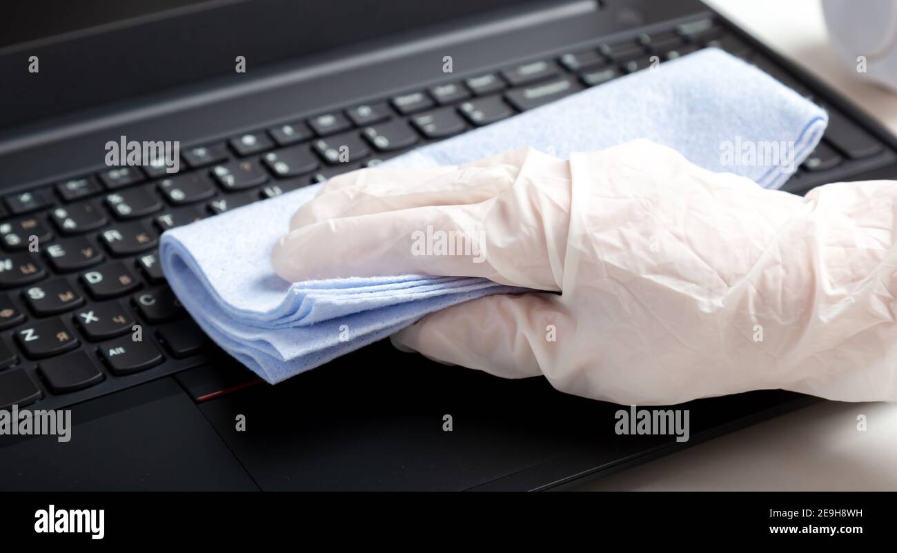 Female hands in gloves disinfecting laptop keyboard using wet