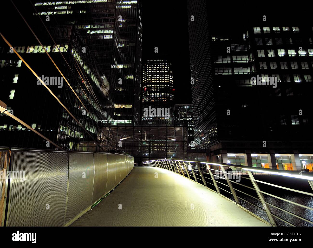 View From The South Quay Footbridge To The Brightly Lit Bank Towers Of Canary Wharf  London England At Night Stock Photo