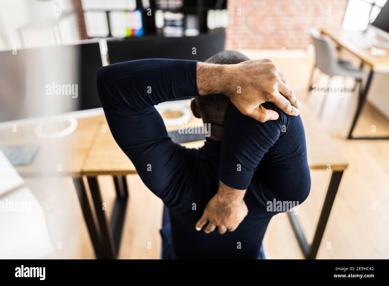 African Employee Man Doing Wellness Fitness Health Stretch At Desk Stock Photo
