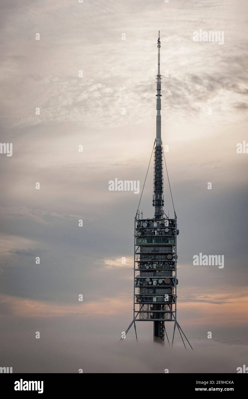 Telecommunications tower Torre de Collserola emerges amid clouds and fog on the Tibidabo hill in  in Barcelona.  It was designed by the architect Sir Stock Photo