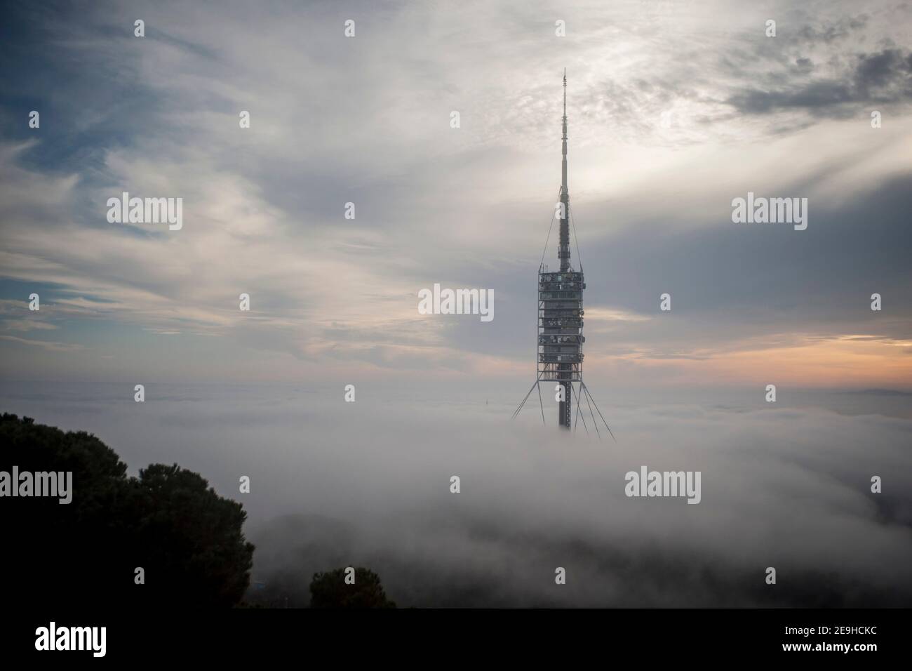 Telecommunications tower Torre de Collserola emerges amid clouds and fog on the Tibidabo hill in  in Barcelona.  It was designed by the architect Sir Stock Photo