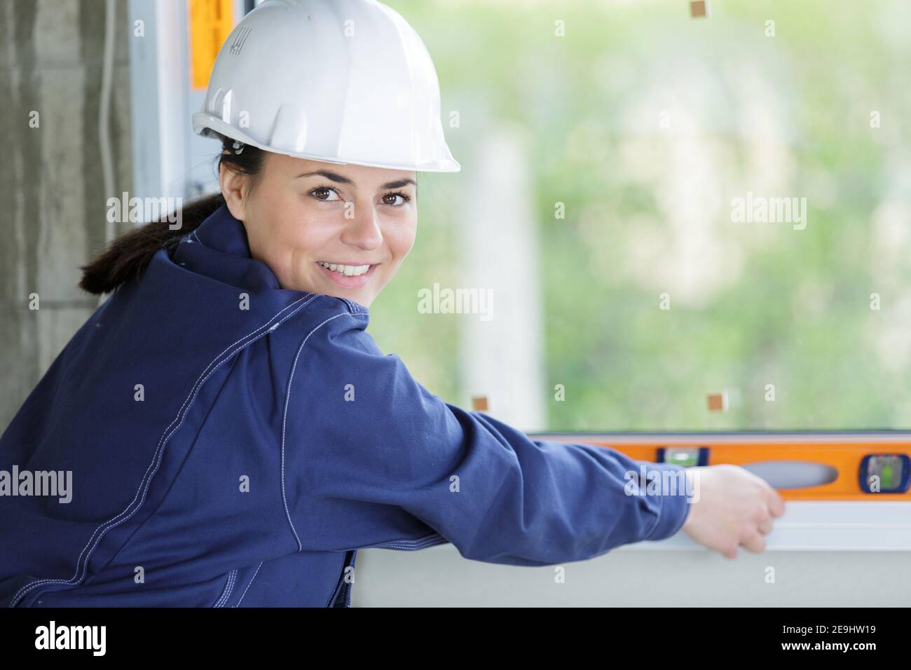 smiling female builder using spirit level Stock Photo