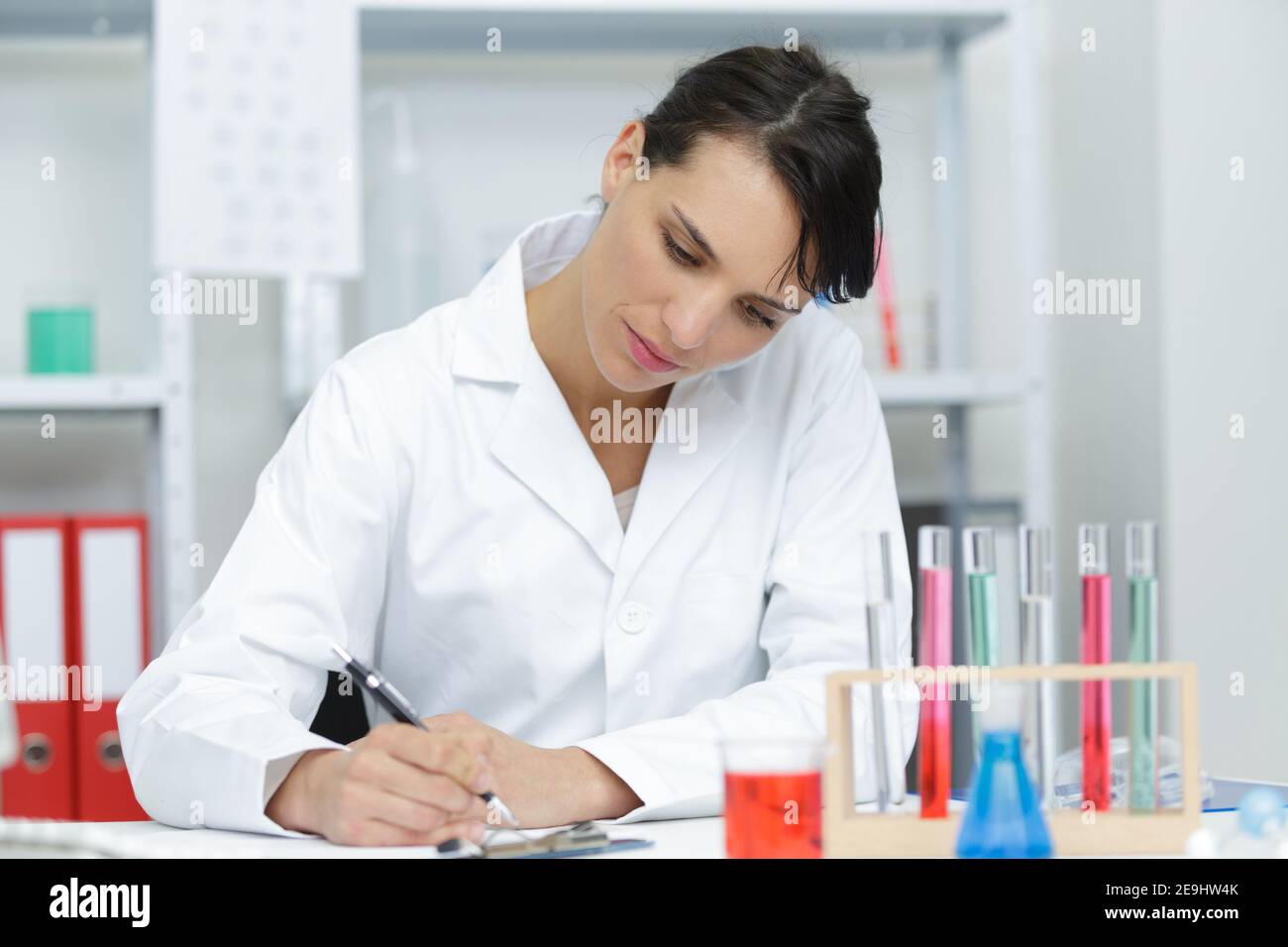 female chemist looking at testtubes with blue liquids Stock Photo Alamy