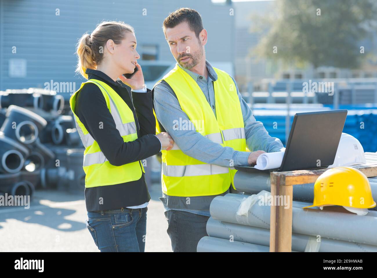 workers looking at laptop leaned on building materials Stock Photo