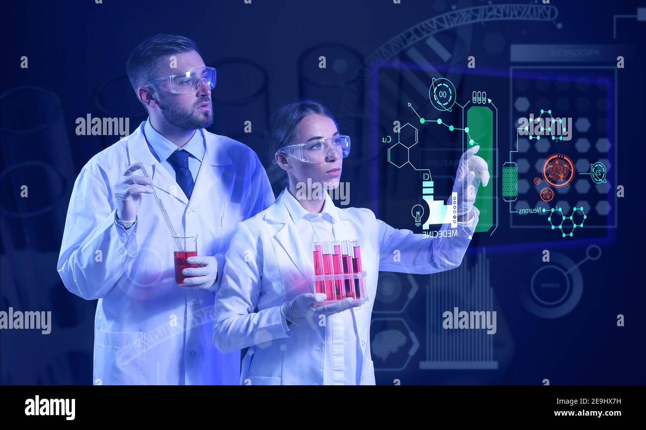Young scientists with samples using virtual screen on dark background Stock Photo