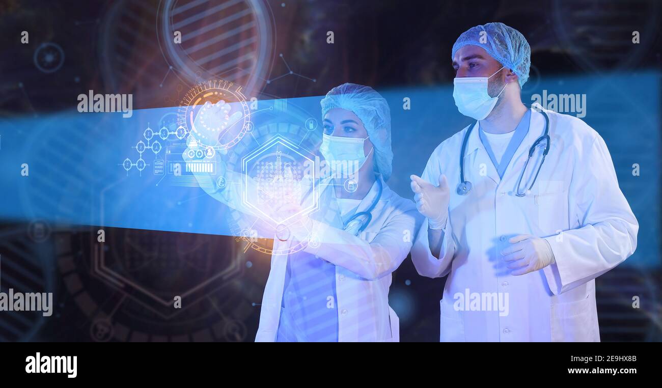 Young scientists using virtual screen on dark background Stock Photo