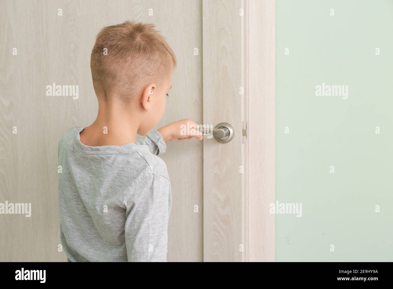 Cute little boy opening door in room Stock Photo - Alamy
