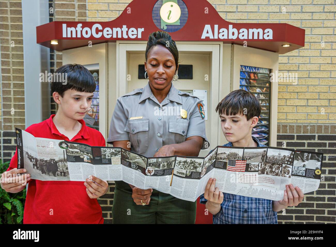 Alabama Scenic Highway 80 Selma to Montgomery Civil Rights Trail,Lowndes Interpretive Center centre Black woman female park ranger,boys looking folder Stock Photo