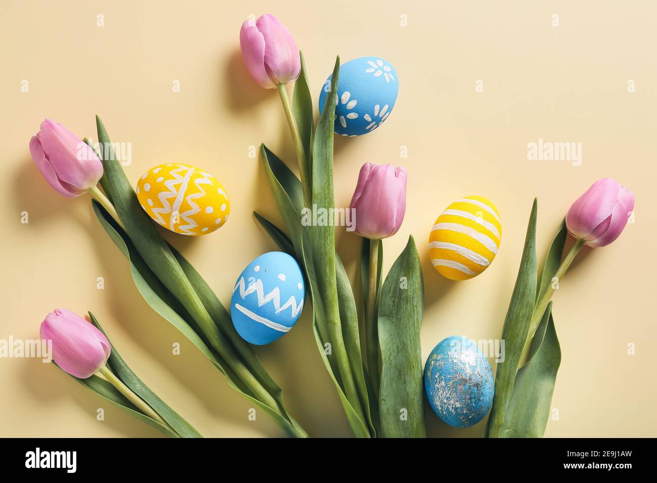 Composition with beautiful Easter eggs and flowers on color background ...