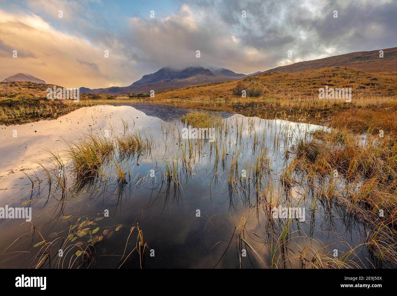 Isle of Skye, Scotland: Morning clouds clearing over the Cuillin mountains with reflections in a pond near Sligachan Stock Photo