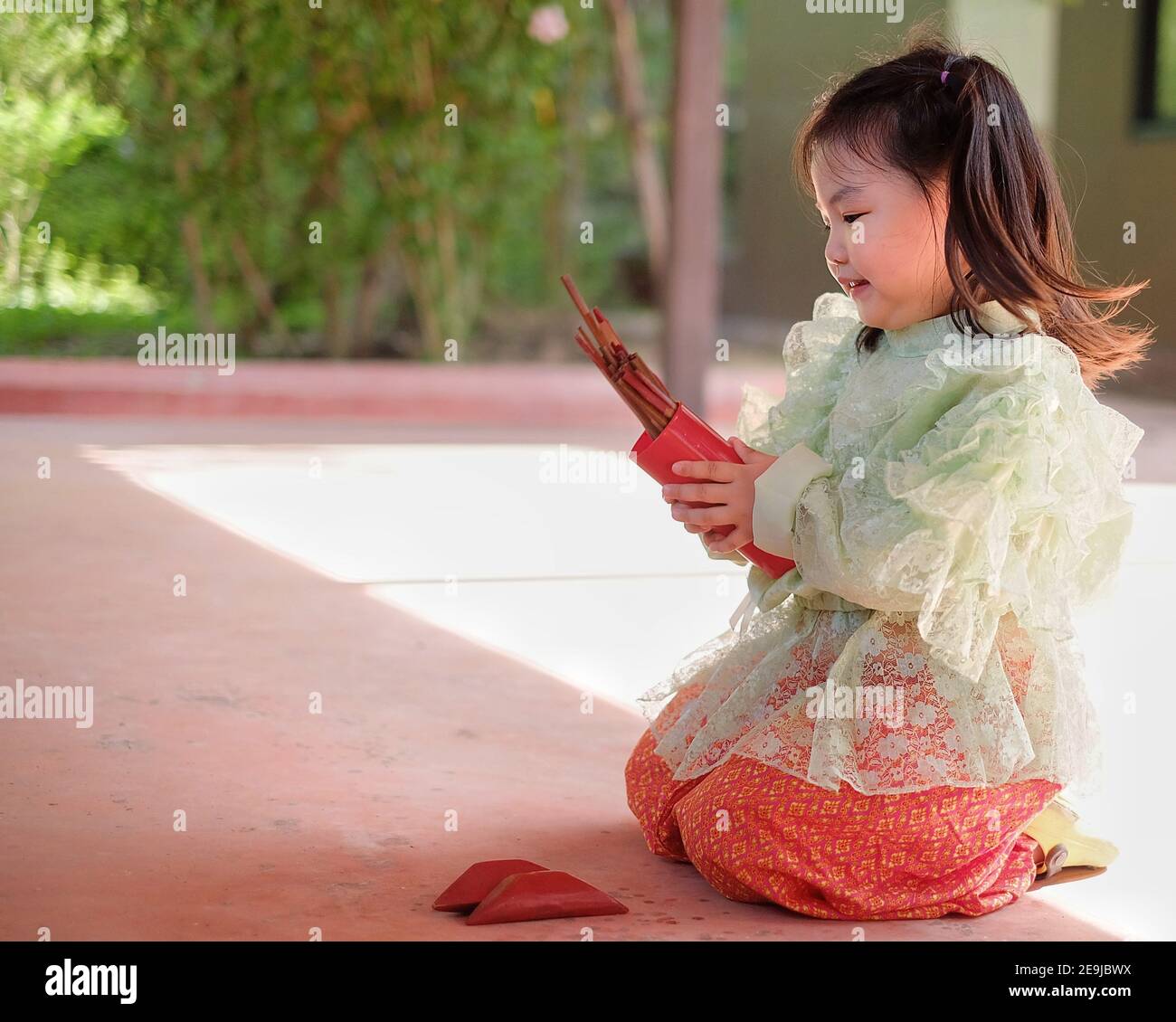 Cute young Asian girls in traditional Thai costumes are shaking chi-chi sticks, also known as Kau chim  or Kau cim sticks during a festive Thai new ye Stock Photo
