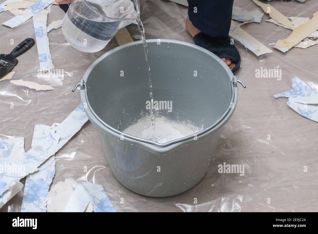 Mixing white plaster in a bucket with a stirrer. Closeup Stock Photo