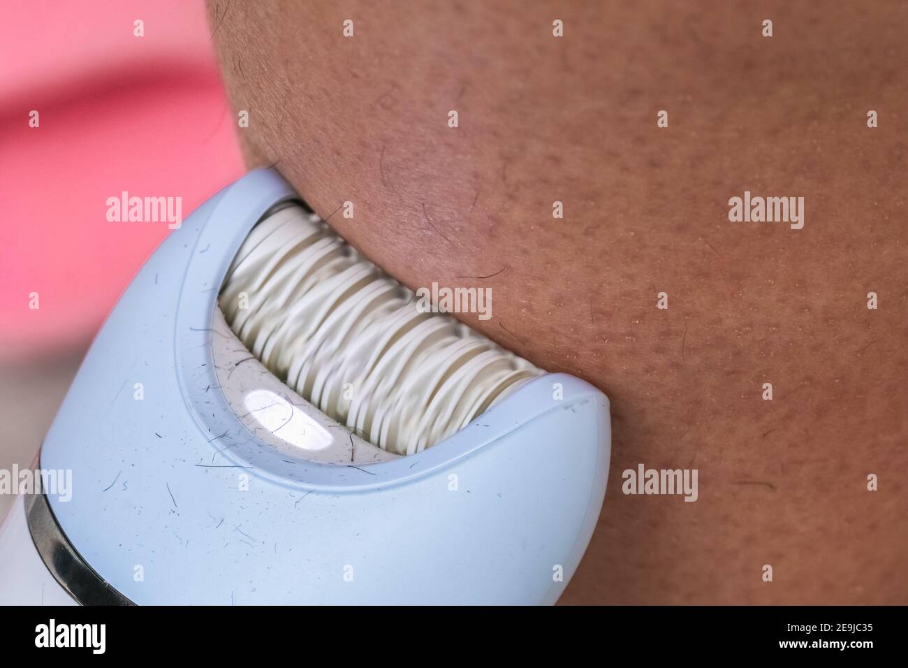 The girl epilates her leg with a white epilator. Depilation. Closeup