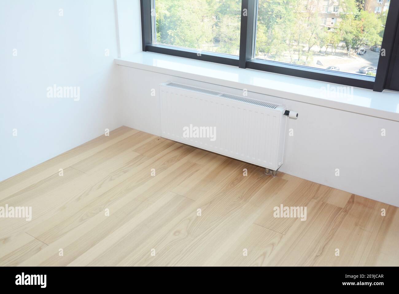 White radiator heating with thermostat for energy saving, wooden floor