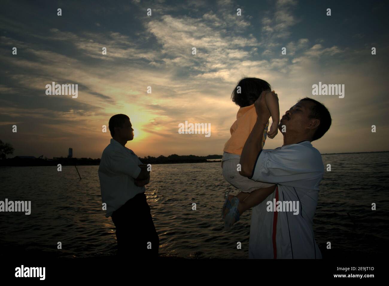 People having a leisure activity, enjoying the relaxing atmosphere before sunset time on a reclaimed land in Pantai Indah Kapuk beach, close to a residential complex in the coastal area of Jakarta, Indonesia. Stock Photo