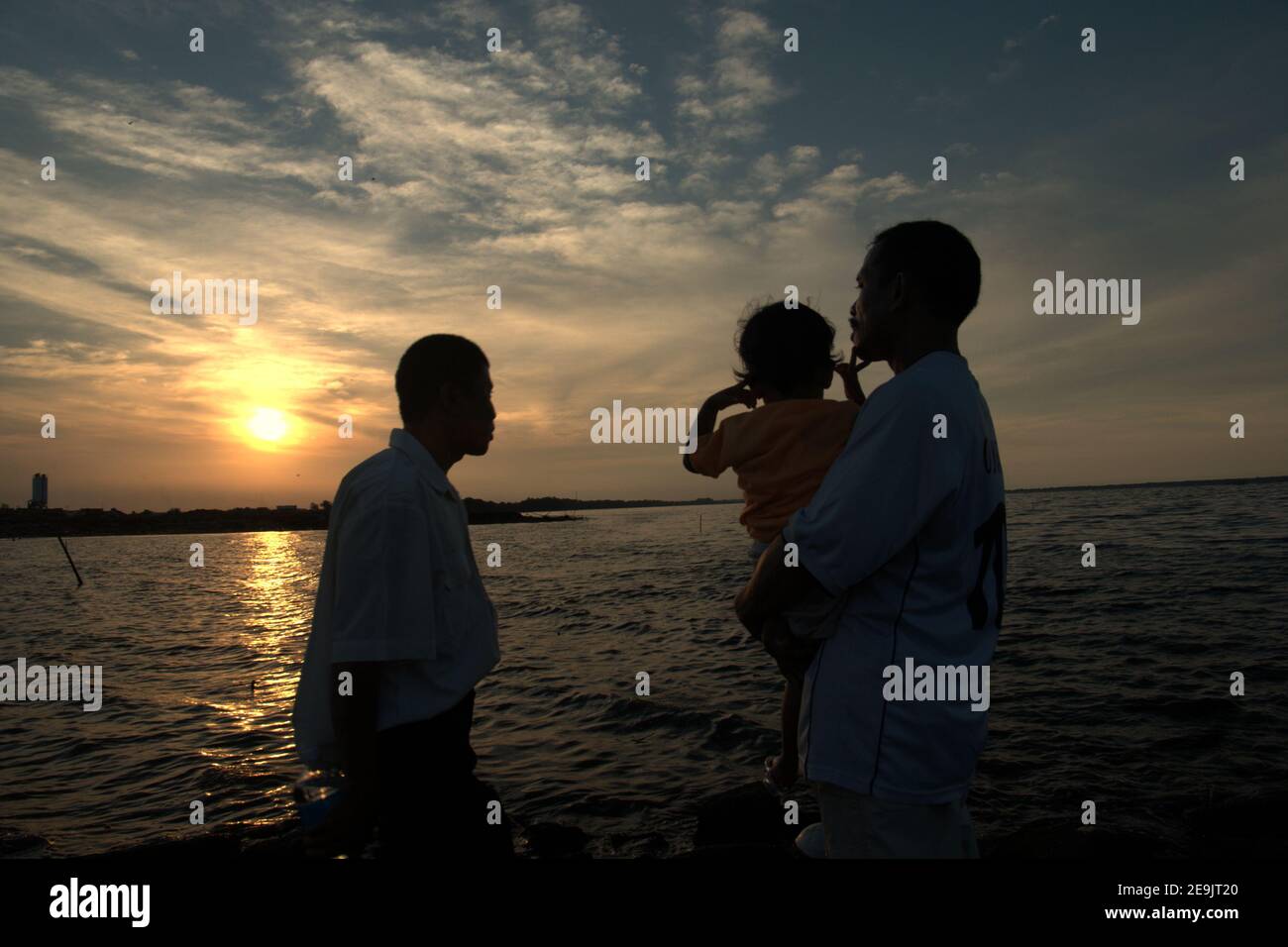 People having a leisure activity, enjoying the relaxing atmosphere before sunset time on a reclaimed land in Pantai Indah Kapuk beach, close to a residential complex in the coastal area of Jakarta, Indonesia. Stock Photo