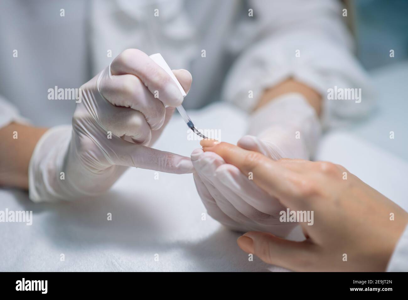 Close up picture of nail artists hands applying nail base Stock Photo
