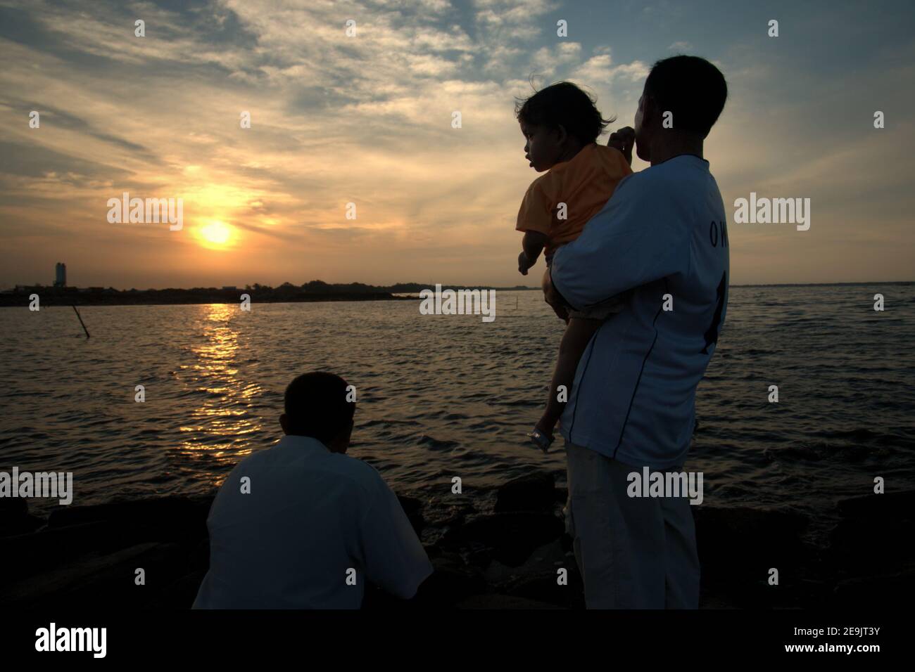 People having a leisure activity, enjoying the relaxing atmosphere before sunset time on a reclaimed land in Pantai Indah Kapuk beach, close to a residential complex in the coastal area of Jakarta, Indonesia. Stock Photo