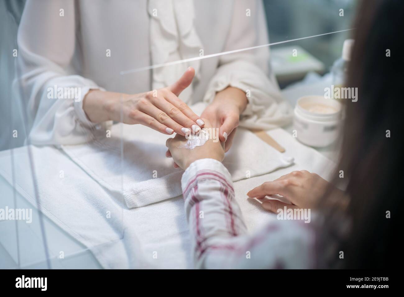 Close up picture of beautician hands applying cream on clients hands Stock Photo