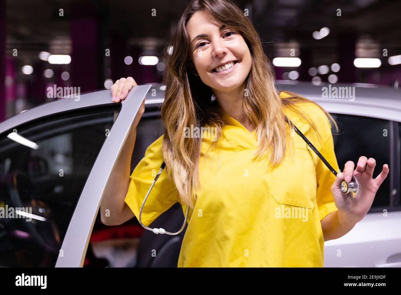 Portrait of young smiling female nurse getting out of her vehicle ready to start work. Space for text. Stock Photo