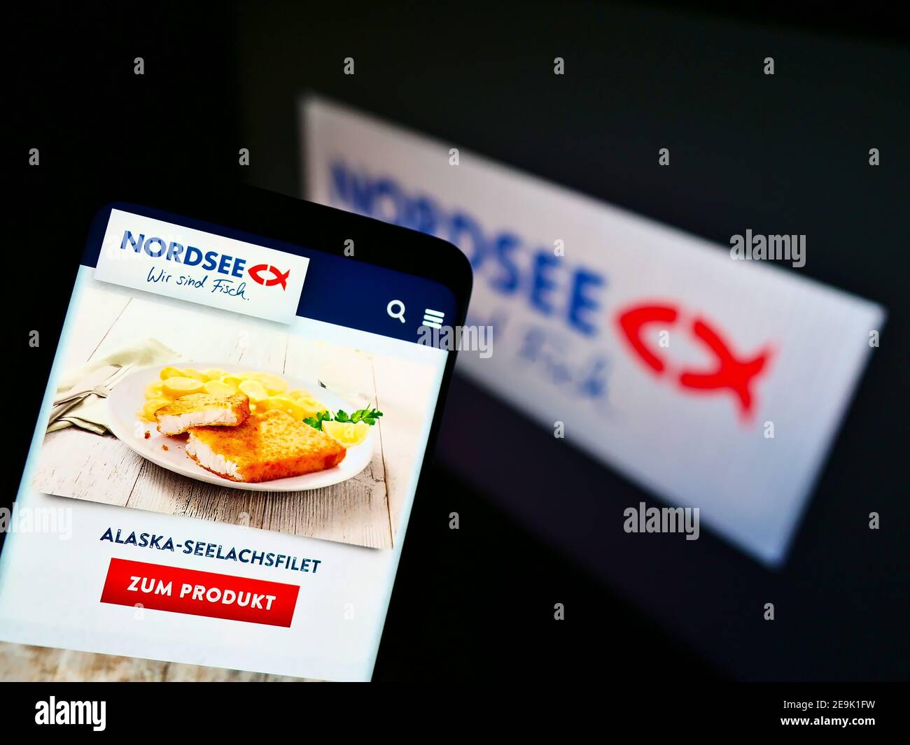 Smartphone with salmon meal of German fast-food restaurant chain Nordsee GmbH (seafood) on display in front of company logo. Focus on phone screen. Stock Photo