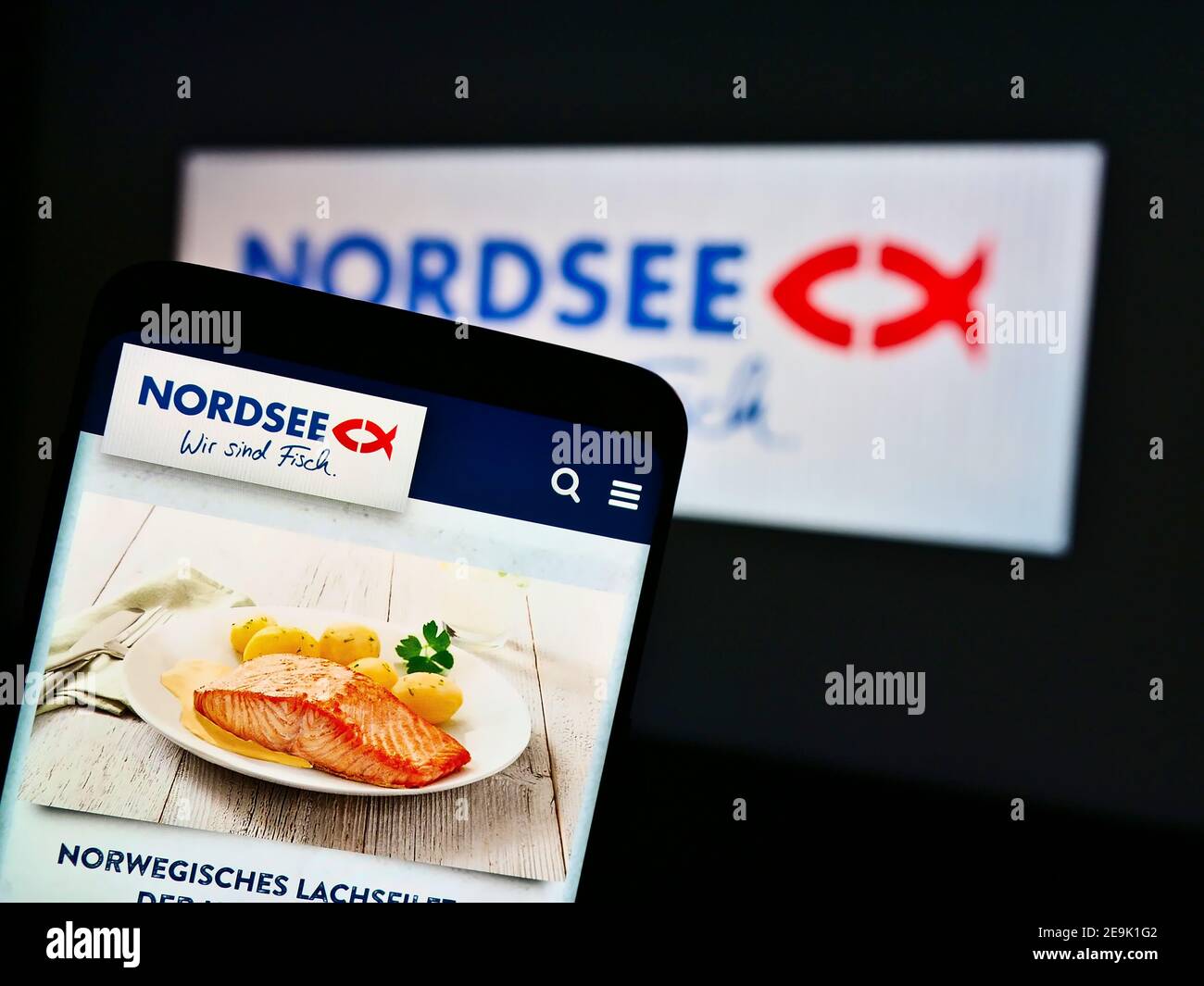 Mobile phone with meal of German fast-food restaurant chain Nordsee GmbH on display in front of company logo. Focus on top center of phone screen. Stock Photo